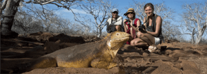 Three travelers photograph a land iguana during their educational journey through the Galápagos Islands.