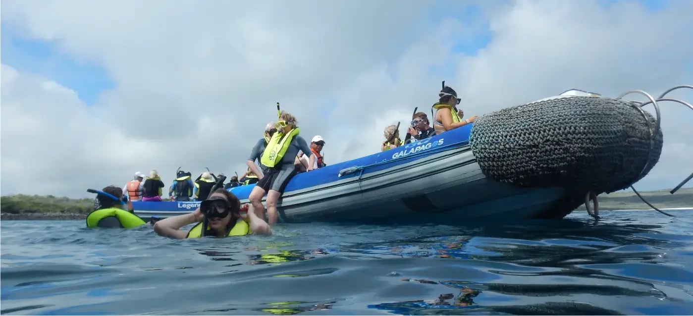 Travelers snorkeling from an inflatable boat in the Galapagos Islands, enjoying a guided marine wildlife adventure in clear ocean waters.