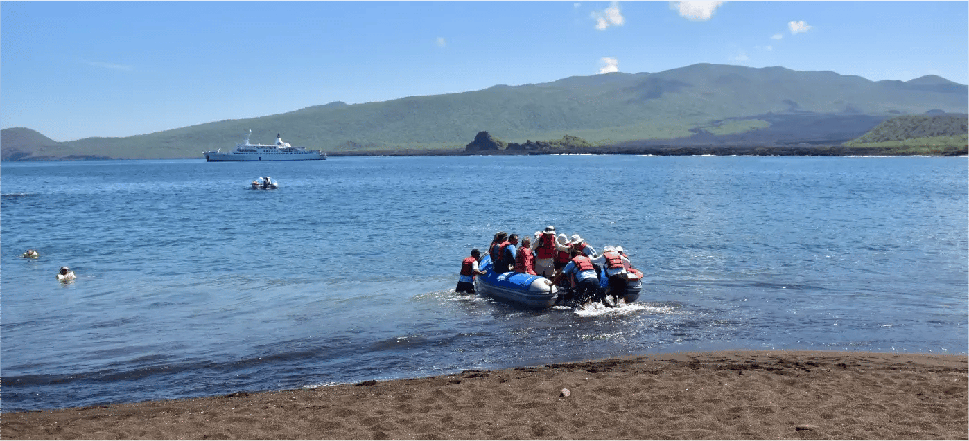 Travelers inside a panga, with the Galapagos Legend Boutique Expedition Cruise in the background.