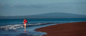 Rabida in Galapagos Islands with a red sand beach and a tourist girl jogging