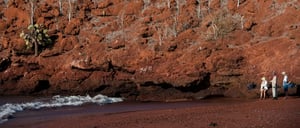 Rabida in Galapagos Islands, view of the red hill and sand with tourist looking around