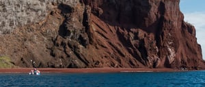 Rabida in Galapagos Islands, view of the red sand and hill with tourist wallking near to the boat